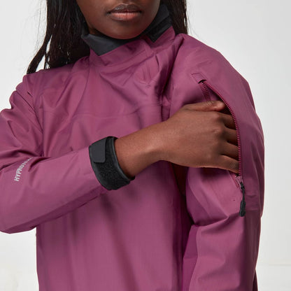 A person wearing a magenta NRS Endurance Splash Jacket - Women's unzips an upper arm pocket on the waterproof jacket.