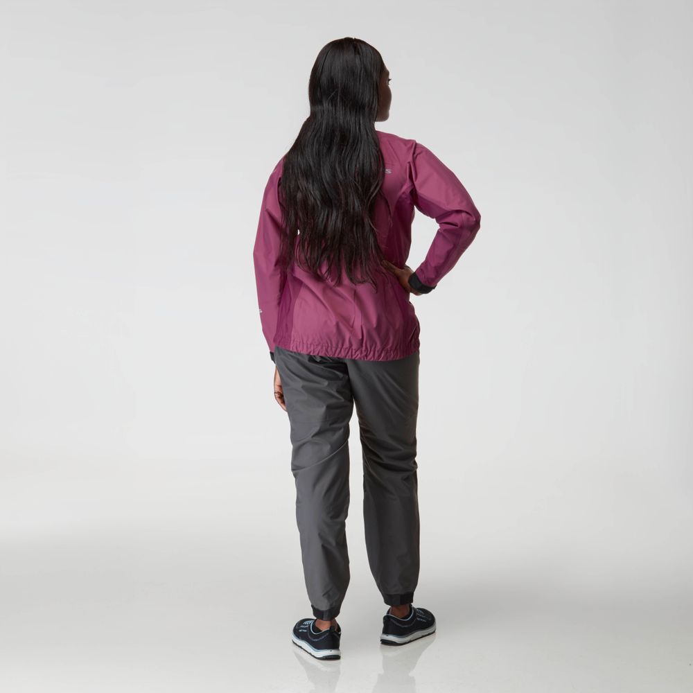 A person stands with their back to the camera, wearing an NRS Endurance Splash Jacket - Women's in magenta, gray pants, and black sneakers against a plain light background.