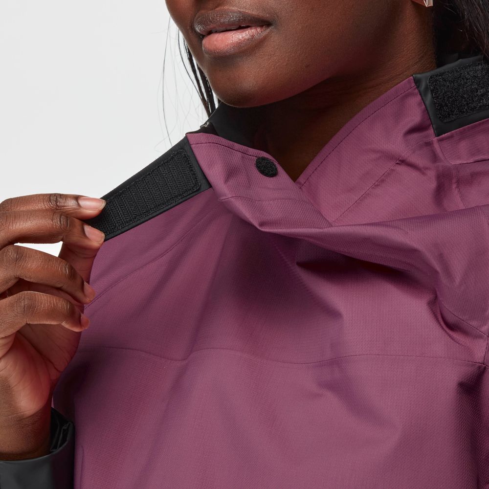 A person fastens the black Velcro collar of an NRS Endurance Splash Jacket - Women's, a purple waterproof jacket.