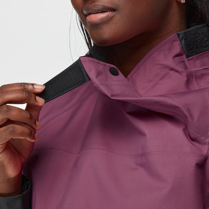 A person fastens the black Velcro collar of an NRS Endurance Splash Jacket - Women's, a purple waterproof jacket.