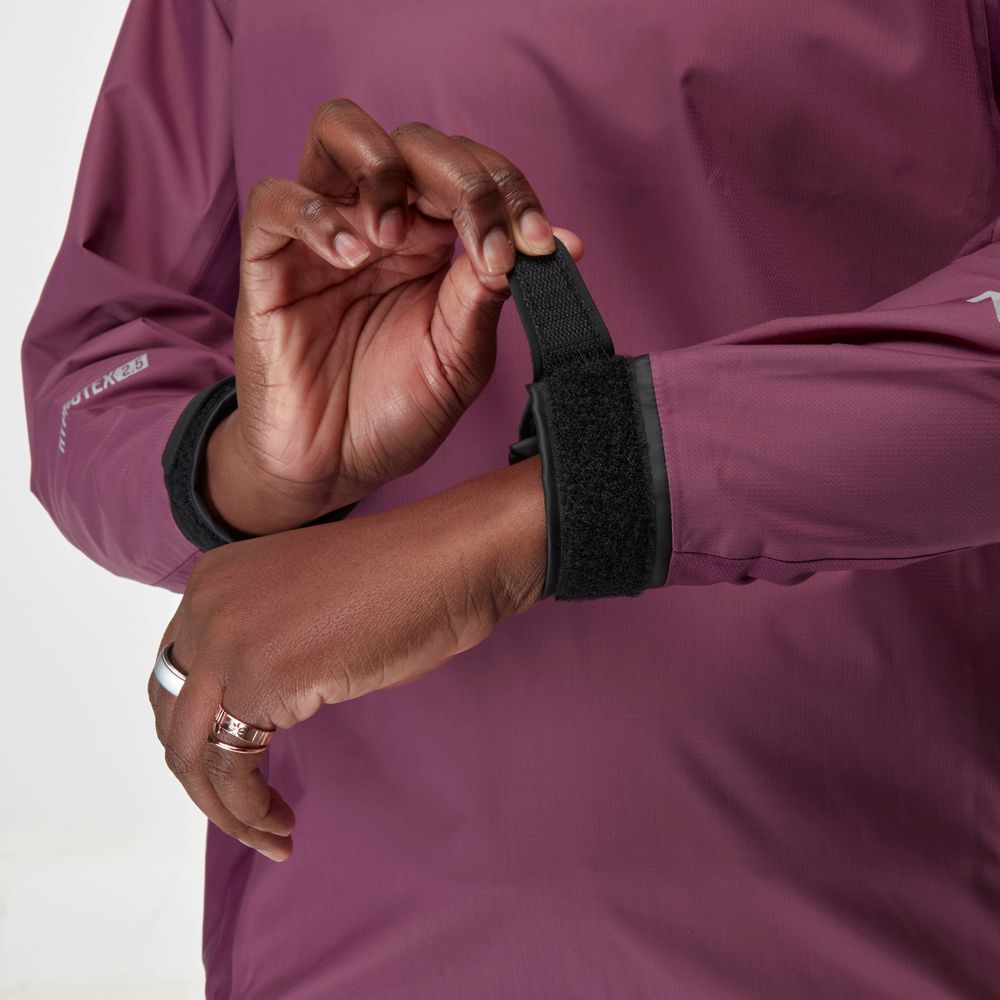 A person adjusts the Velcro cuff on a mauve NRS Endurance Splash Jacket - Women's, ideal as a waterproof splash jacket.