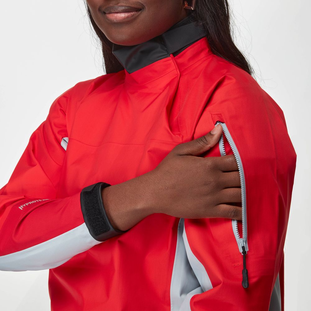 A person wearing the NRS Endurance Splash Jacket - Women's in red unzips a pocket on the upper sleeve.