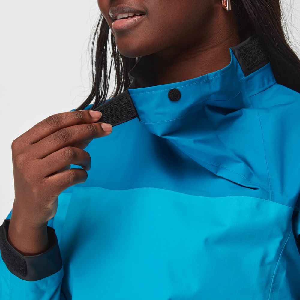 A person adjusts the black Velcro collar strap on the NRS Endurance Splash Jacket - Women's in bright blue, with their face partially visible and background blurred.