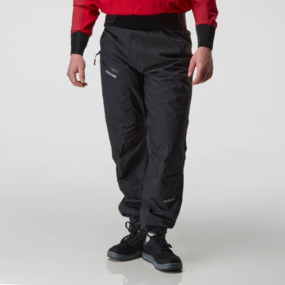 A person wears a red jacket and black NRS Endurance Splash Pant - Men's, crafted from waterproof, breathable HyproTex fabric, with black shoes, standing against a plain white background.