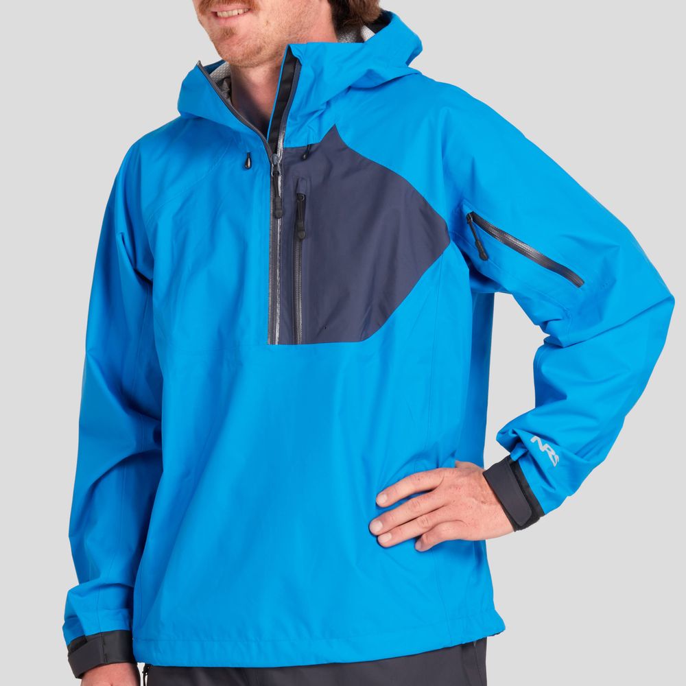 A person wearing the NRS High Tide Jacket - Men's stands against a plain backdrop. The bright blue jacket has a dark gray chest pocket, zippered sleeve pocket, and adjustable hood, showcasing its waterproof breathable design ideal for adventurers.