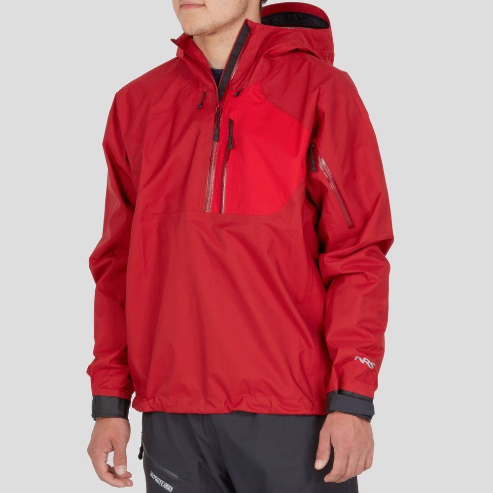 A person wearing the NRS High Tide Jacket - Men's in red with zipped pockets, perfect for paddling, and dark gray pants.