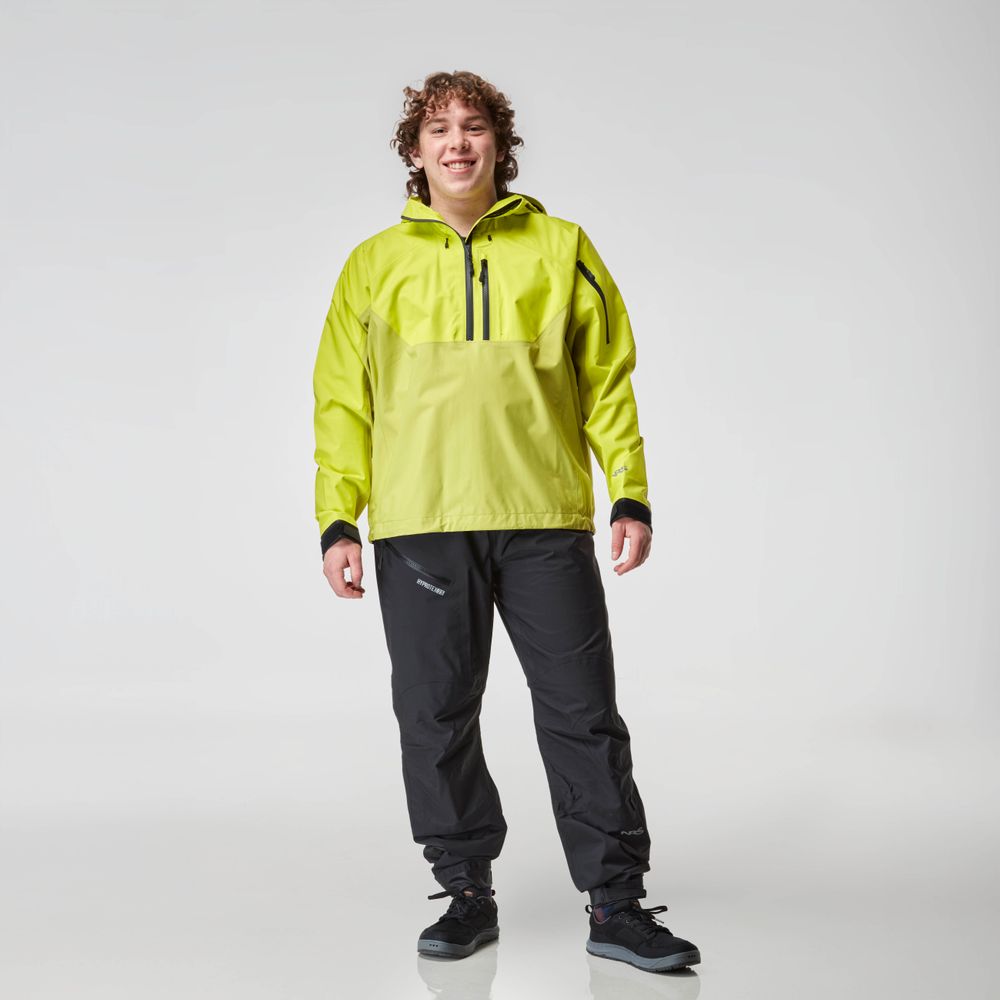 A man in a bright green NRS High Tide Jacket and black pants smiles against a plain white background.