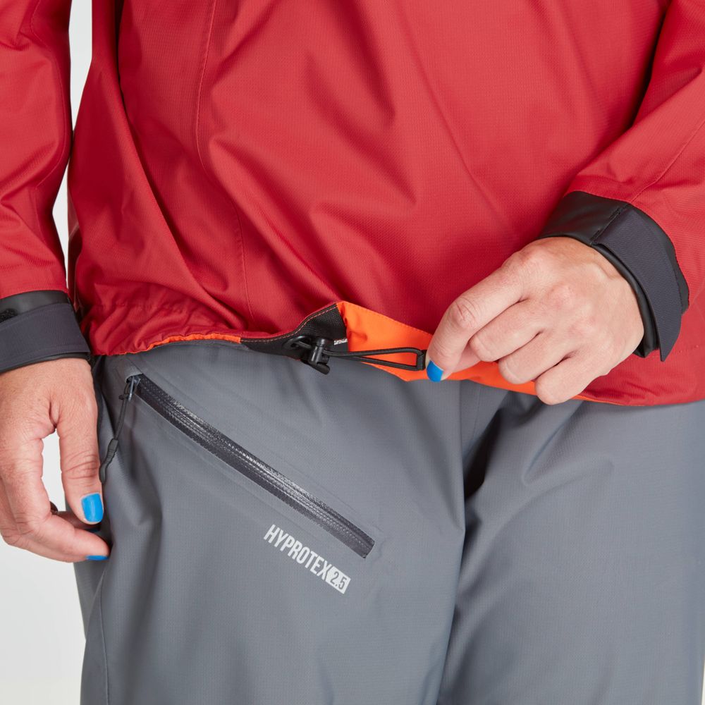 A person in gray pants with a "HYDRO-TEX" logo adjusts the drawstring on an NRS High Tide Jacket - Women's. They have blue-painted nails.