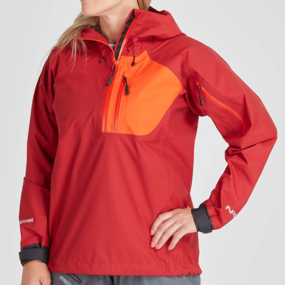 Confidently sporting the NRS High Tide Jacket - Women's in vibrant red and orange, a person stands with hand on hip. This waterproof paddler's cut jacket is stylish and adventure-ready with its multiple zippers and pockets.