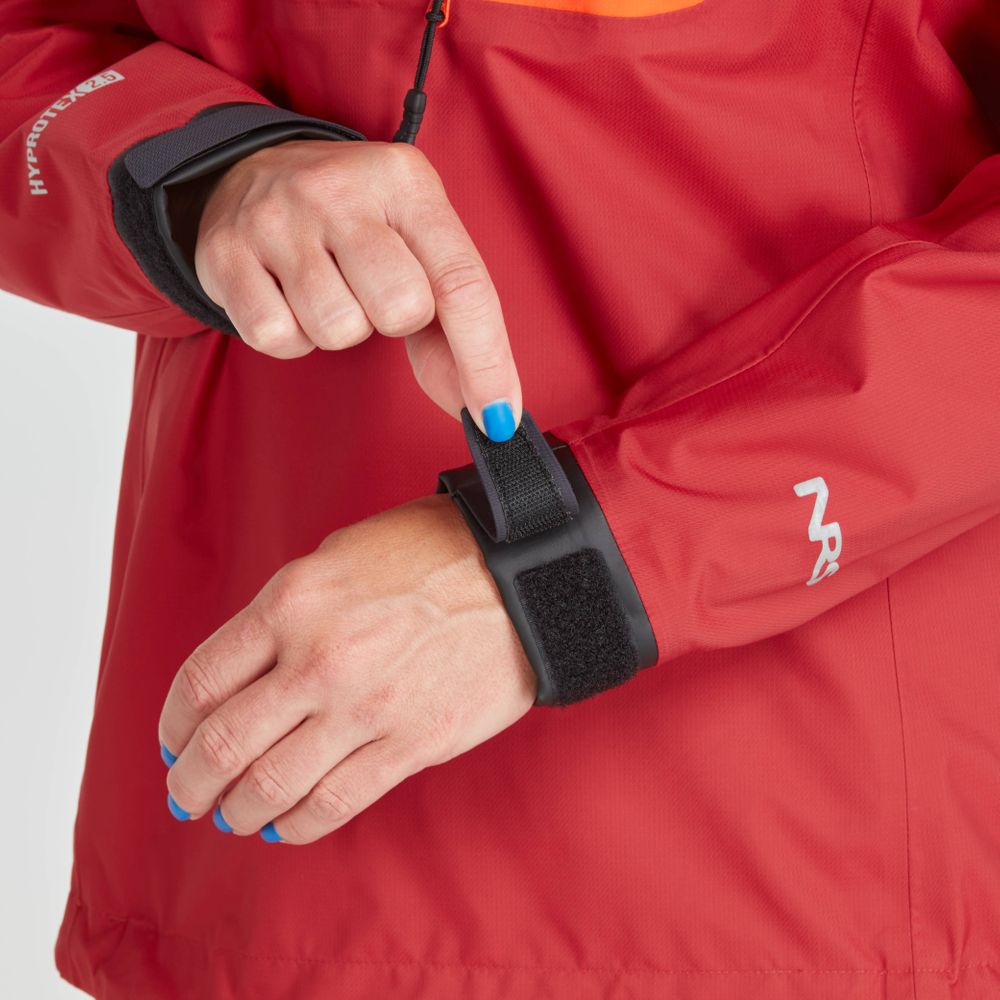 Wearing the NRS High Tide Jacket - Women's, featuring an adjustable hood for breathable protection, a person with blue painted nails adjusts a black Velcro wrist strap.