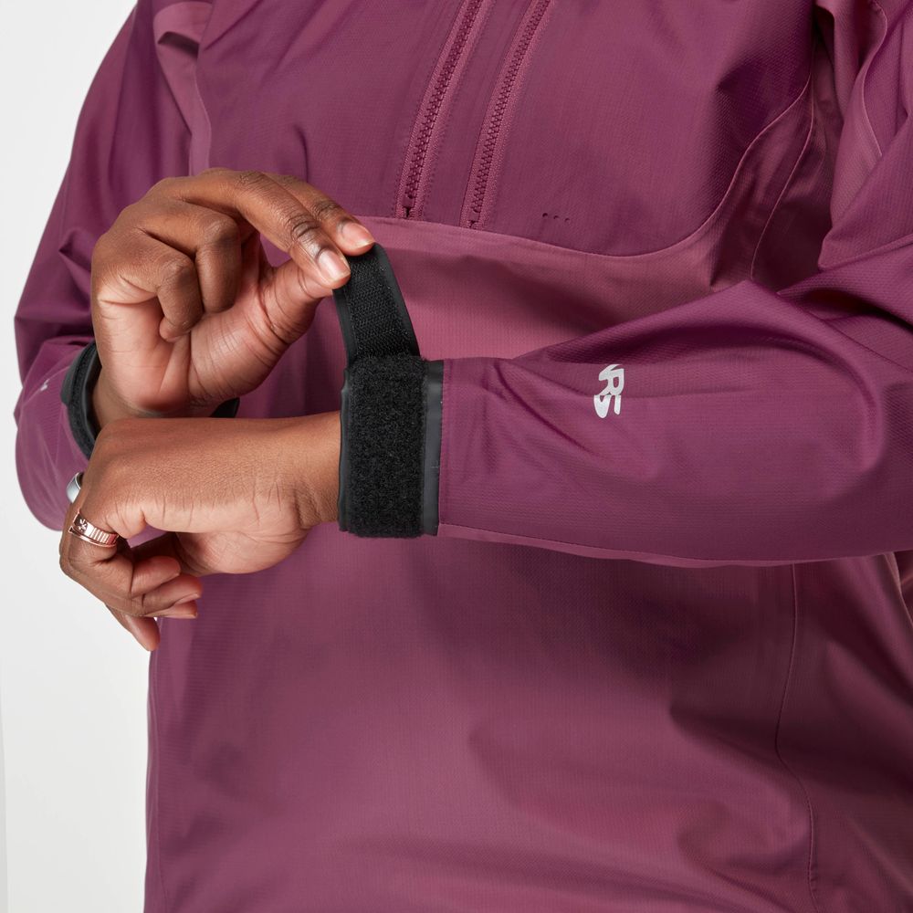 A person adjusts the velcro strap on the sleeve of a purple High Tide Jacket for women by NRS, which is waterproof.