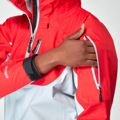 A person adjusts the sleeve zipper on the NRS High Tide Jacket - Women's, a red and gray waterproof splash jacket designed for breathable protection in any weather.