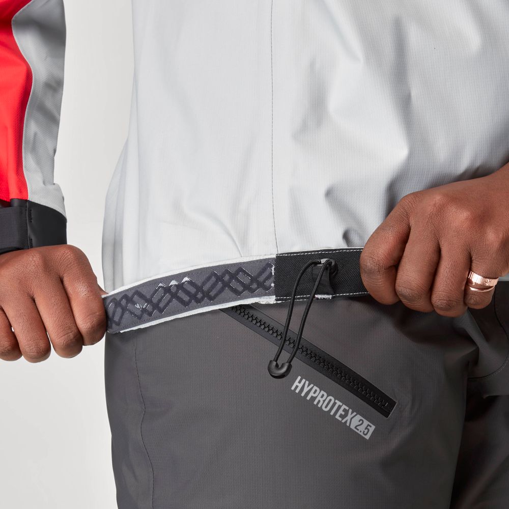 A person adjusts the elastic drawcord on the hem of a grey and white NRS High Tide Jacket - Women's.