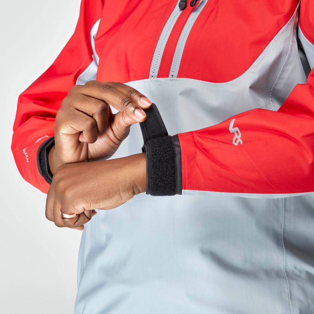 A person adjusts the black Velcro cuff on the sleeve of an NRS High Tide Jacket - Women's in red and gray, highlighting its comfortable fit and waterproof design.