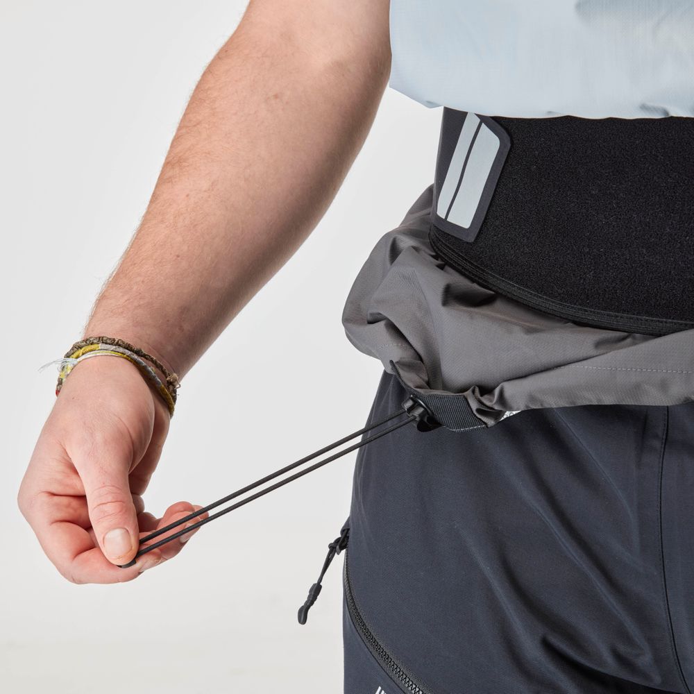 A person tightens a gray waist bag over dark pants and a light shirt, with a black waist support visible, complementing their NRS Stratos Short Sleeve Paddling Jacket.