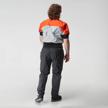 A person with curly hair faces away, wearing an NRS Stratos Short Sleeve Paddling Jacket in red and gray with neoprene neck and arm seals, black pants, and sneakers against a plain white background.