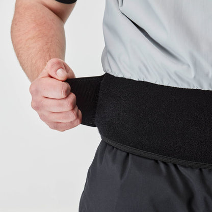 A person in a gray shirt and dark pants secures a black velcro belt while wearing the NRS Stratos Short Sleeve Paddling Jacket, which features neoprene neck and arm seals for waterproof, breathable protection.