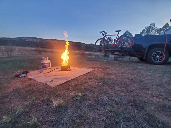 A VolCanNo Tacana Combo by LavaBox is parked next to a campfire in the middle of a field, despite campfire bans.