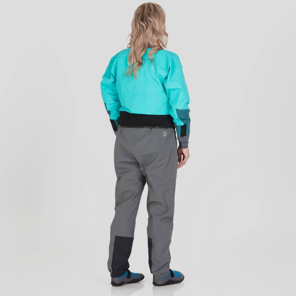 A woman stands facing away in an NRS REV (GORE-TEX Pro) Drytop, teal with gray pants, showcasing its waterproof breathable performance.