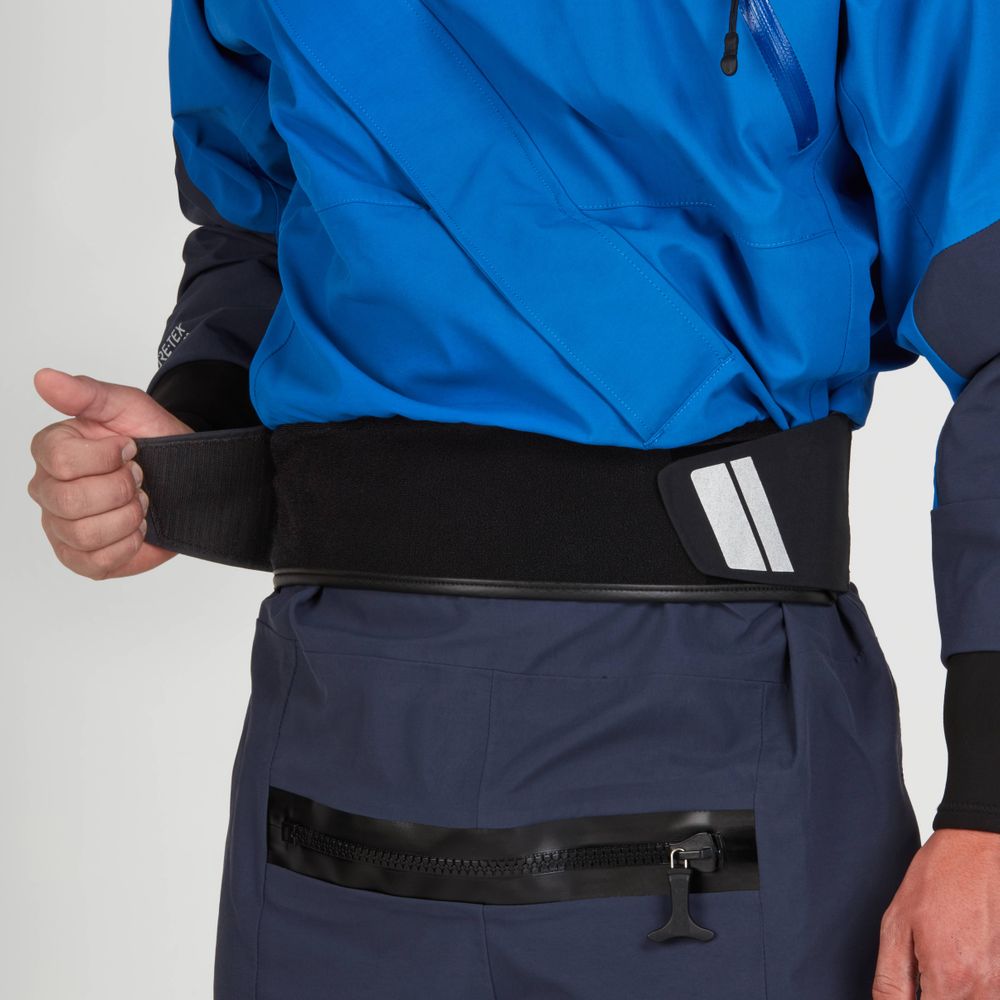 Adjusting the waist strap of the NRS Axiom (GORE-TEX Pro) Drysuit - Men's, the person highlights its recycled nylon fabric and zipper pocket, along with reflective details for enhanced visibility.