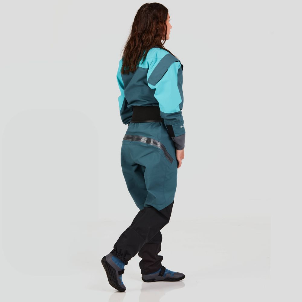A woman confidently strides in an NRS Axiom GORE-TEX Pro Drysuit, teal and black, against a plain background, viewed from the side.