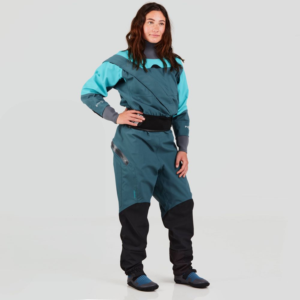 Wearing the NRS Axiom GORE-TEX Pro Drysuit in teal and black with blue shoes, a person stands against a plain background, ready for any adventure with its waterproof, windproof, and breathable technology.