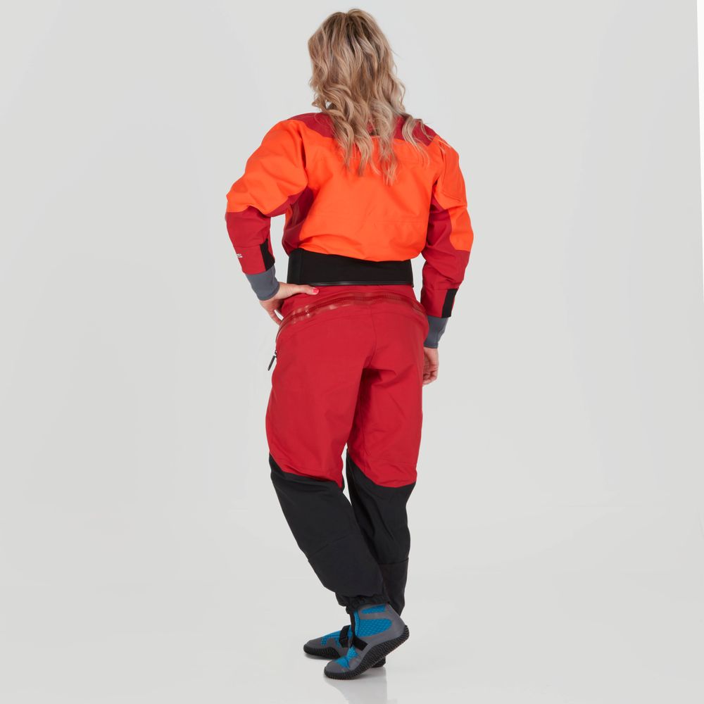 The individual in a vibrant orange and red Axiom GORE-TEX Pro Drysuit by NRS, featuring black accents, stands poised against a neutral backdrop, showcasing its waterproof, windproof, and breathable design.