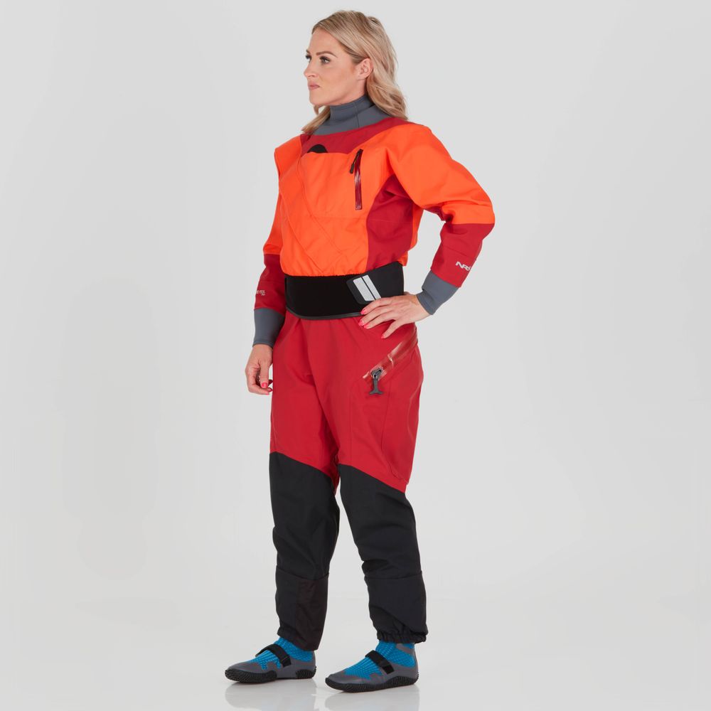 A woman wearing the NRS Axiom GORE-TEX Pro Drysuit in orange and red stands against a plain background, facing slightly left.