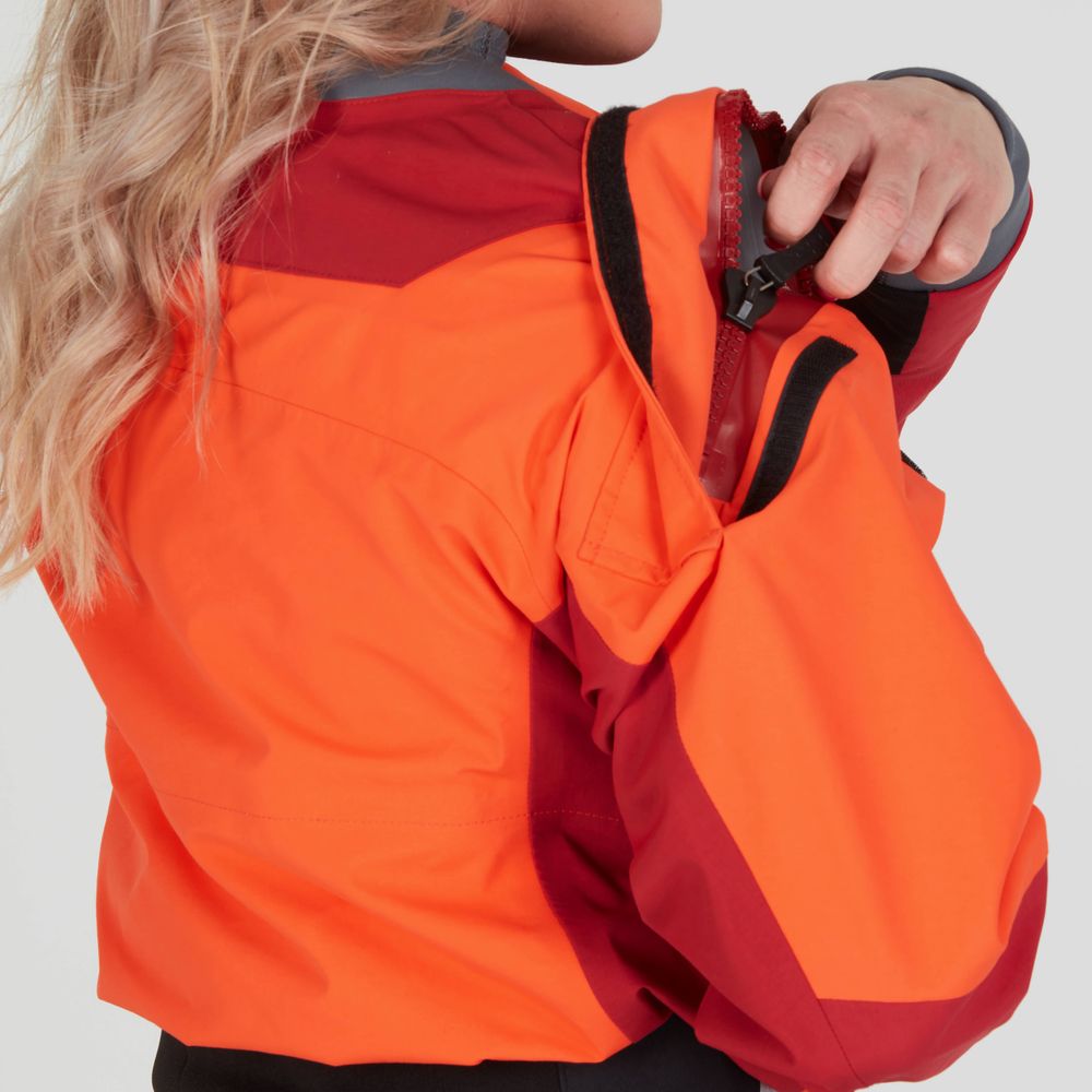 A woman wearing the NRS Axiom GORE-TEX Pro Drysuit adjusts a zipper on her shoulder.