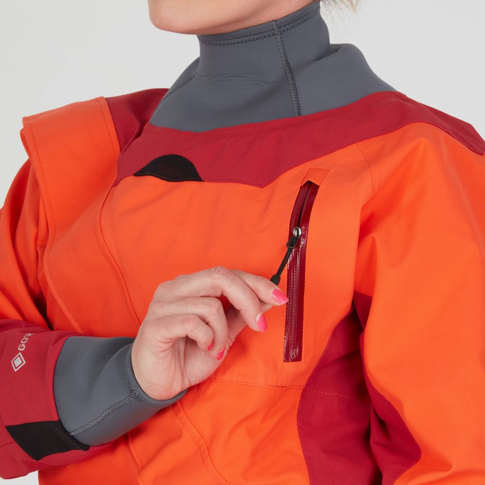 A woman wearing an NRS Axiom GORE-TEX Pro Drysuit with orange and red tones, complemented by gray accents, zips a chest pocket. Featuring waterproof-windproof-breathable materials and a high collar, it's designed for optimal protection.
