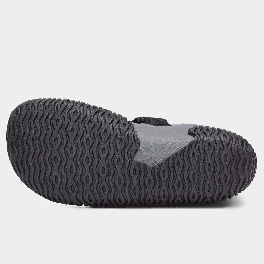 The image shows the NRS Paddle Wetshoe for women, featuring a neoprene design with a textured black sole and wave-pattern tread. The upper part is gray and black.