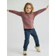 A child with long hair in a mauve long-sleeve shirt, similar to the Toddler Bamboo Shade Hoody by Free Fly, stands arms outstretched against a plain background, highlighting its stylish comfort and UPF 50+ sun protection.