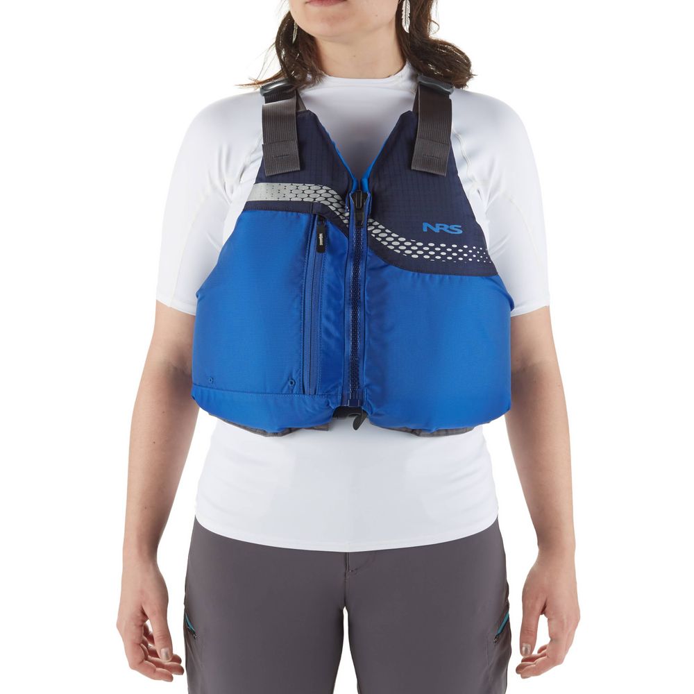 A person wearing a blue NRS Vista PFD, US Coast Guard certified, over a white shirt and gray pants stands against a plain white background.