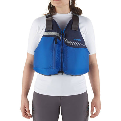 A person wearing a blue NRS Vista PFD, US Coast Guard certified, over a white shirt and gray pants stands against a plain white background.
