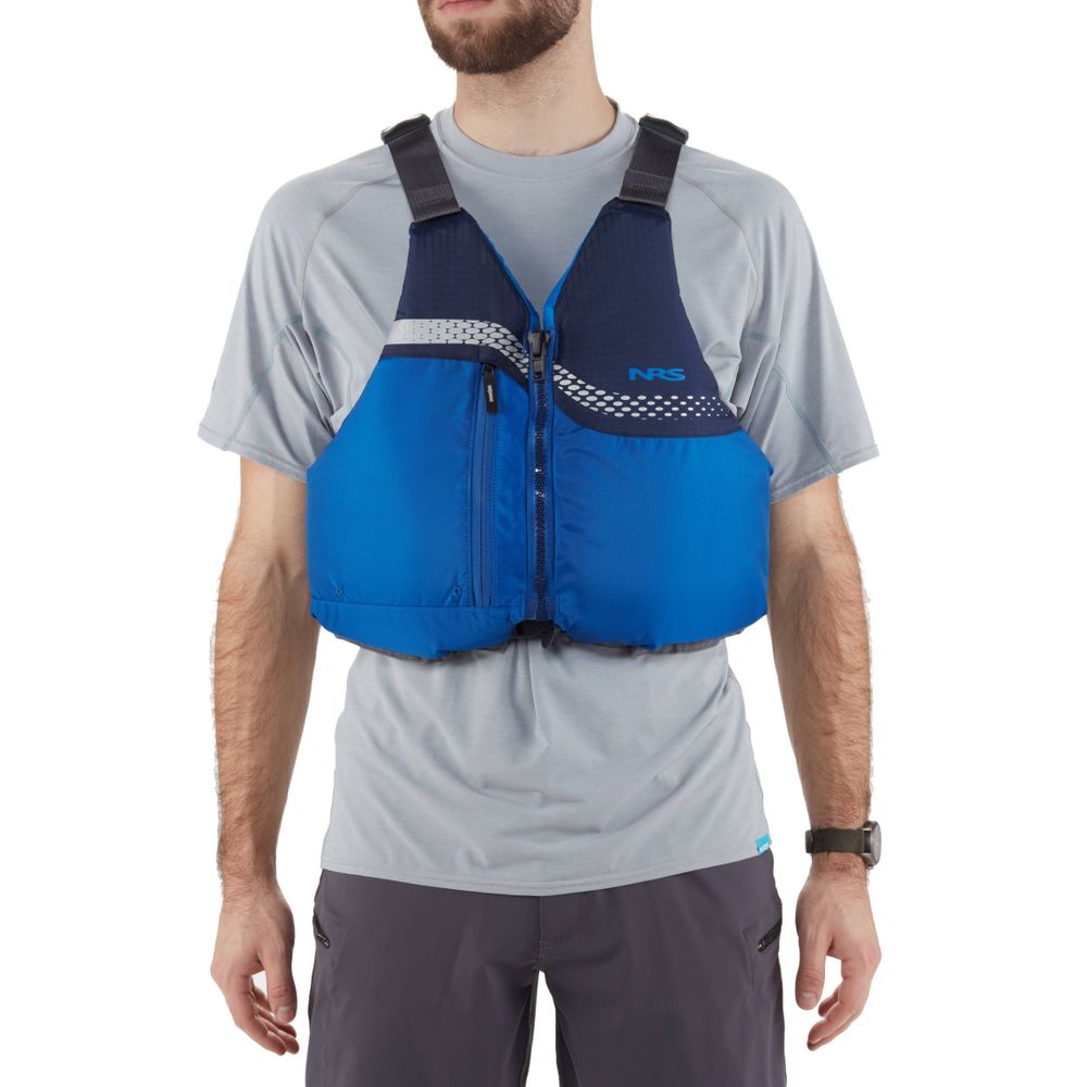 A person wearing a blue NRS Vista PFD over a light gray shirt and dark gray pants. This US Coast Guard-certified life jacket has a front zipper and black adjustable straps for safety and comfort.