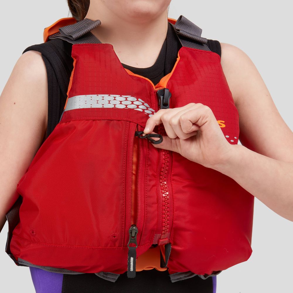 A young person is adjusting the zipper of a red Vista Youth PFD by NRS, made from durable 400 denier nylon, against a plain background. This Type III flotation device ensures enhanced safety.