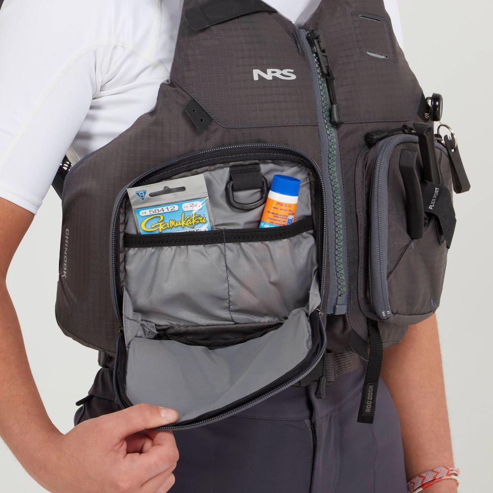 A person wears the NRS Chinook Fishing PFD in gray, with its open front pocket revealing sunscreen and a small pack of chewing gum inside.