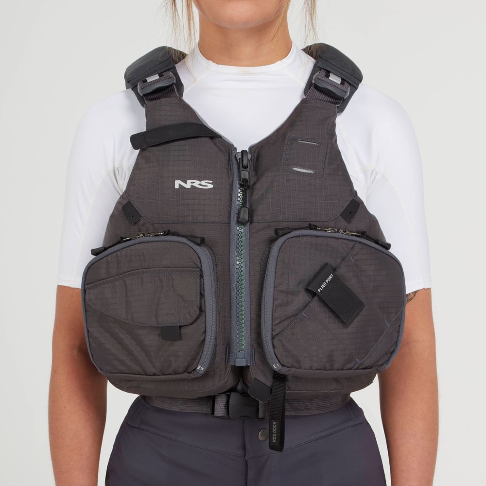 A person wearing an NRS Chinook Fishing PFD in dark gray over a white top, showcasing multiple pockets and zippers.