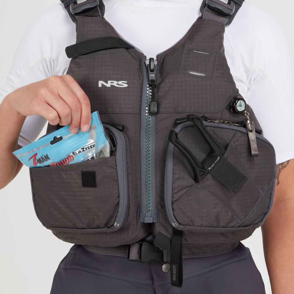A person in an NRS Chinook Fishing PFD puts a pack of bait into a front pocket, with multiple fishing tools attached to the vest.