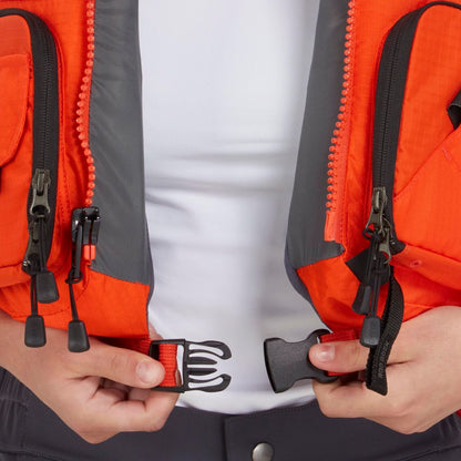 A person wearing the NRS Chinook Fishing PFD, an orange and gray life vest, fastens the black front buckle with both hands.