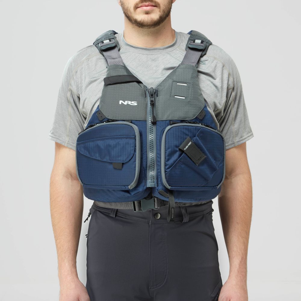 A man in a gray t-shirt and black pants models the NRS Chinook Fishing PFD, a blue and gray life jacket with multiple front pockets, against a plain background.