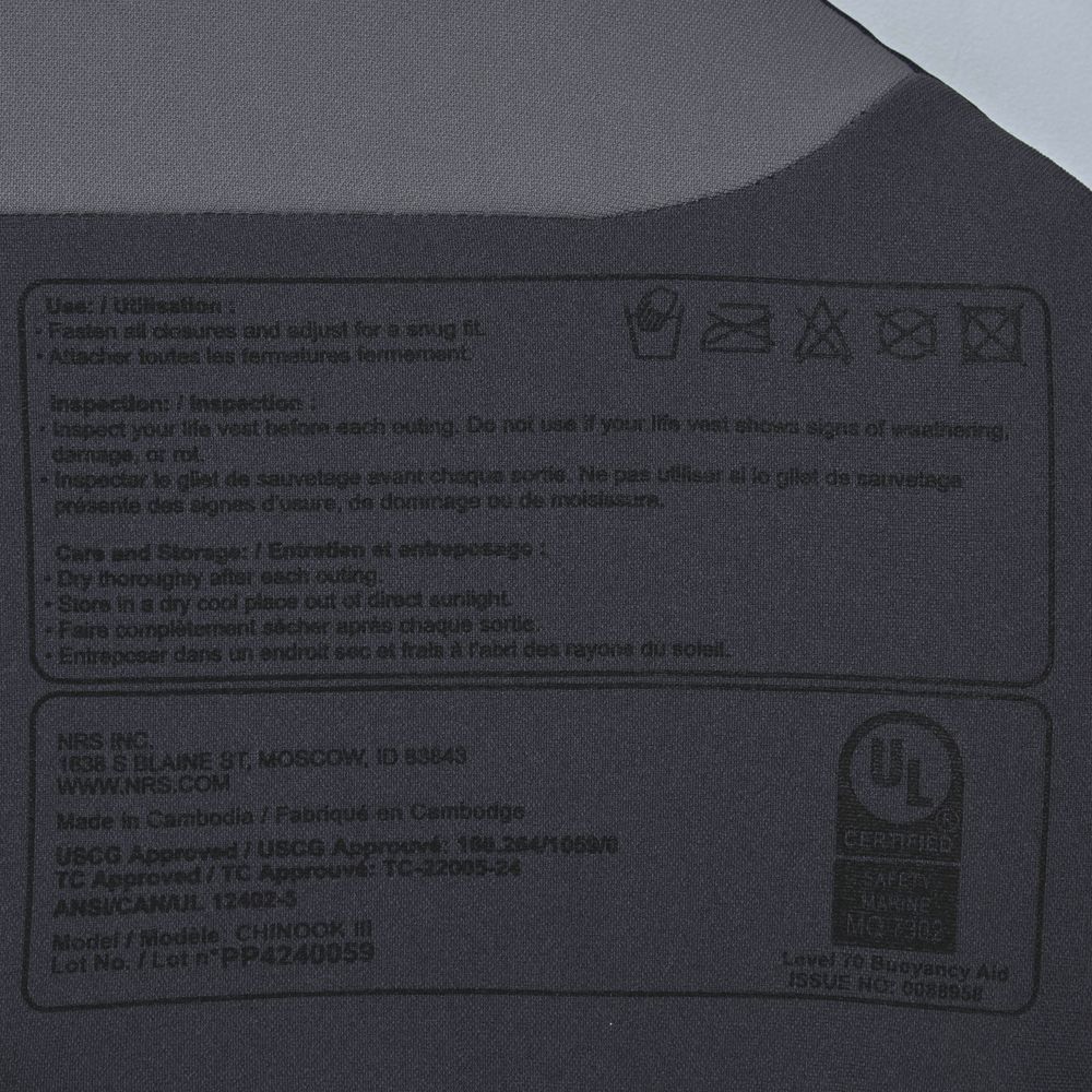 Close-up of a grey fabric label on the NRS Chinook Fishing PFD, featuring usage instructions and certification details, proudly made in Cambodia.