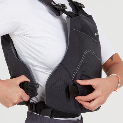 A person in a white shirt fastens the buckle on an NRS Vapor PFD life jacket, getting ready to paddle.