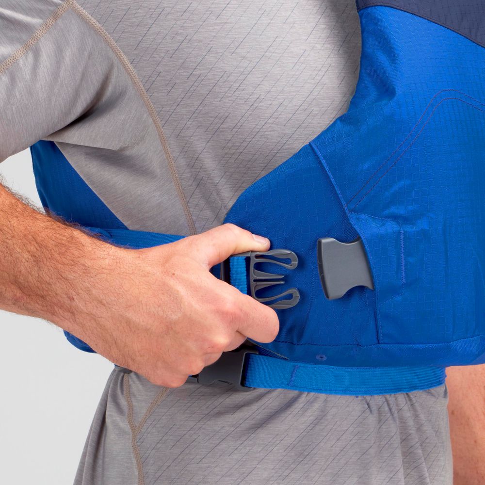 A person in a gray shirt secures the buckle of an NRS Vapor PFD blue life jacket around their waist, getting ready to paddle.