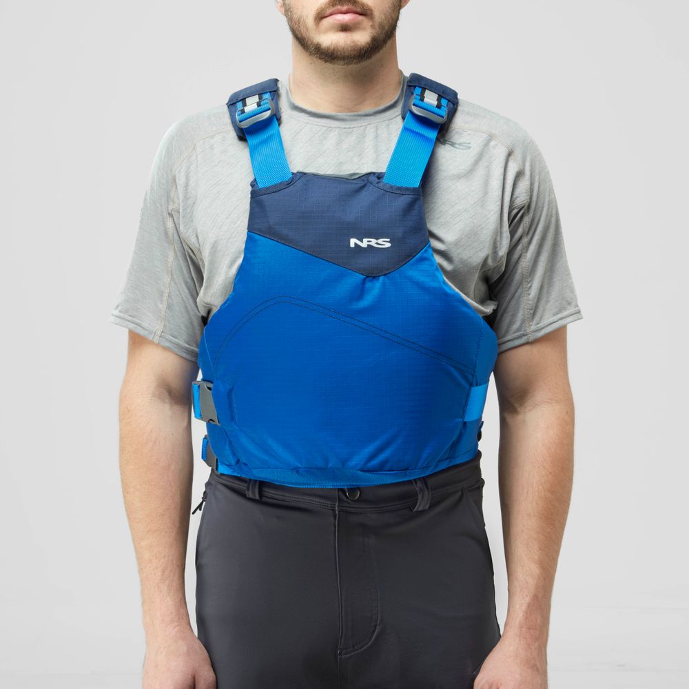 A person wearing an NRS Vapor PFD life jacket in blue over a gray short-sleeve shirt and black pants, facing forward against a plain background.