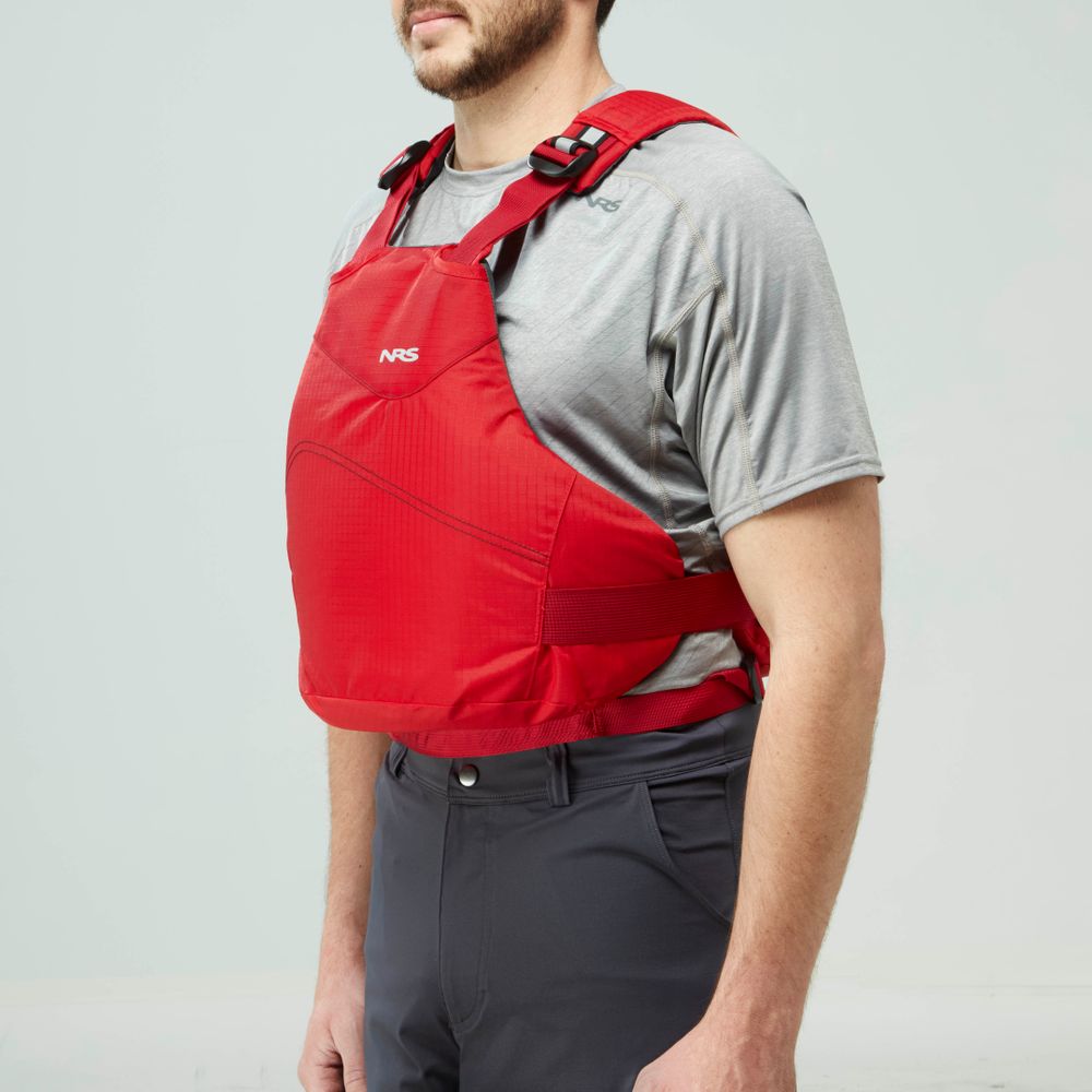 A person wearing an NRS Vapor PFD life jacket over a gray short-sleeve shirt and dark pants stands against a plain light background.