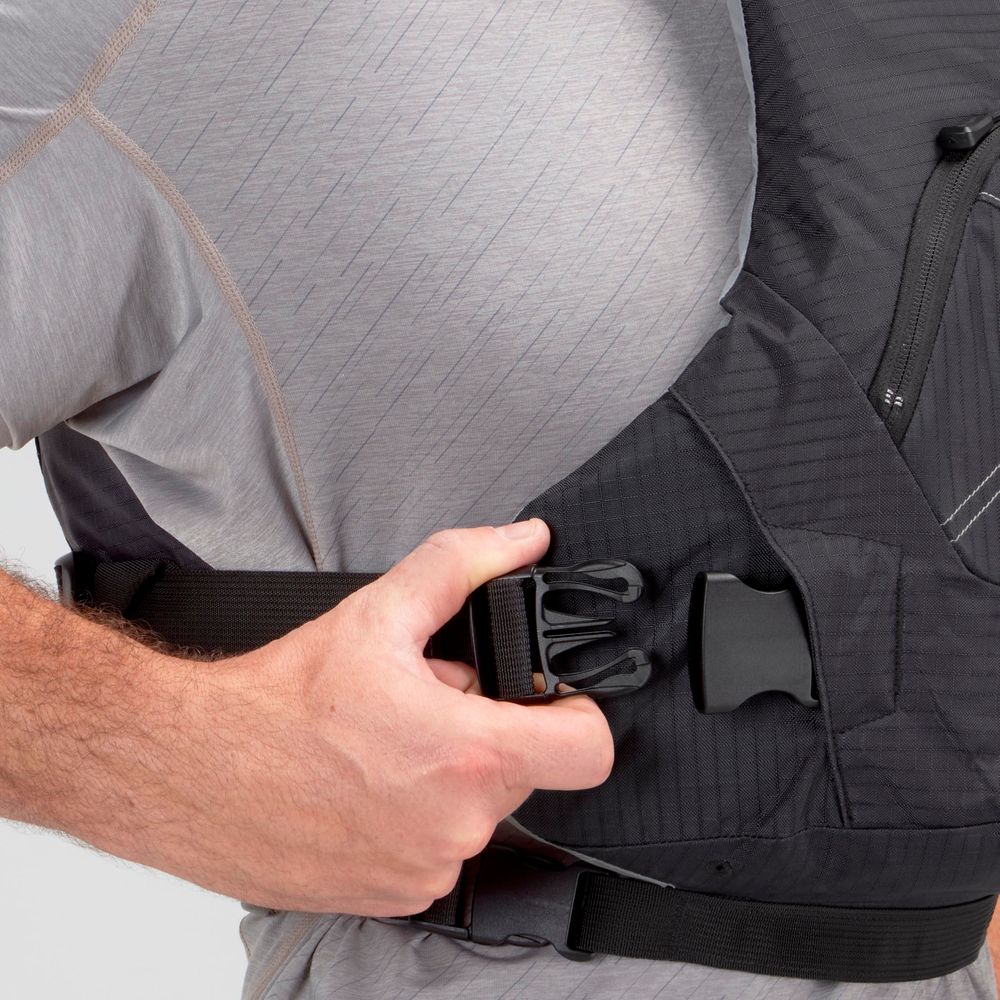 A person fastens the buckle of a black NRS Ion PFD life jacket while wearing a light gray shirt.