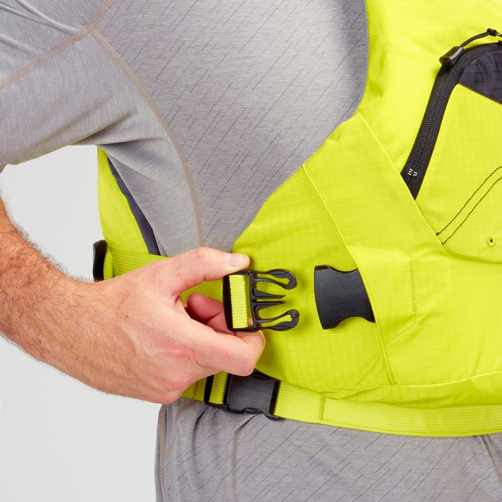 A person in a gray outfit tightens the side strap of a yellow NRS Ion PFD life jacket using an adjustable buckle.