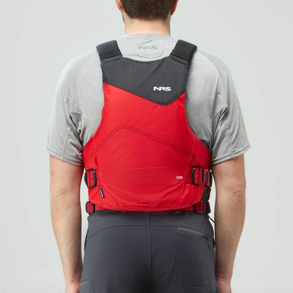 A person in a gray shirt and dark pants is seen from behind, wearing a red NRS Ion PFD life jacket with black shoulder straps.