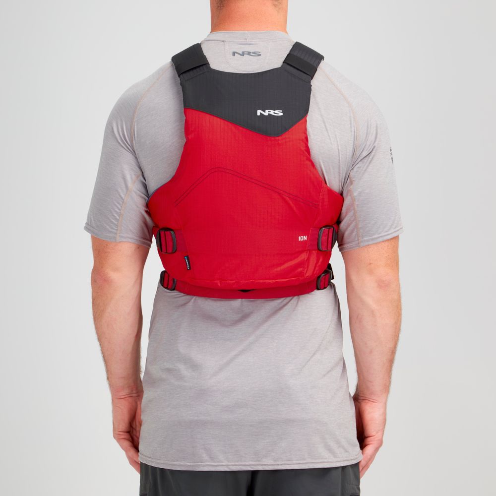 Someone wearing an NRS Ion PFD, a red and black Type III life vest with ultra-soft foam for comfort, is seen from the back over a gray t-shirt.